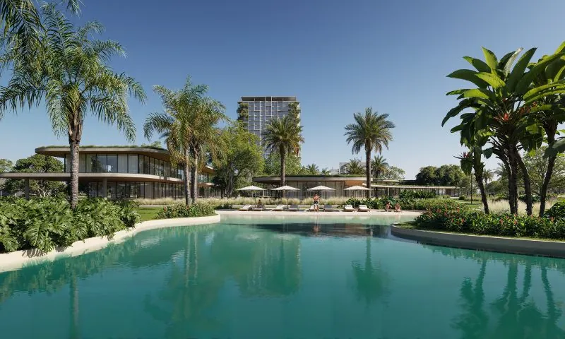 Perspectiva do Porto Belo Lagos: lago cercado de palmeiras, com edifícios baixos e uma torre ao fundo